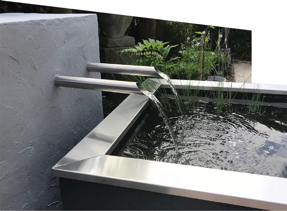 Gerader Wasserauslauf aus Edelstahl, eingebaut in eine Gartenmauer, erhältlich mit oder ohne integriertem Wasserpuffer