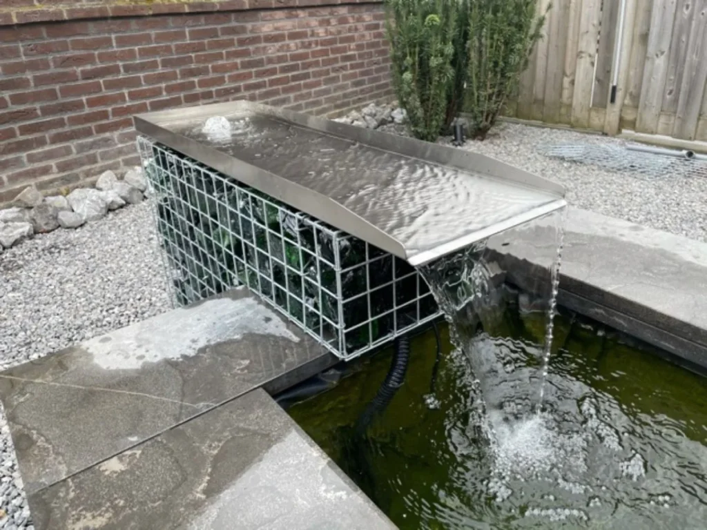 Moderner Bachlauf-Wasserfall aus Edelstahl, montiert auf einer Gabione, als stilvolles Wasserelement im Garten