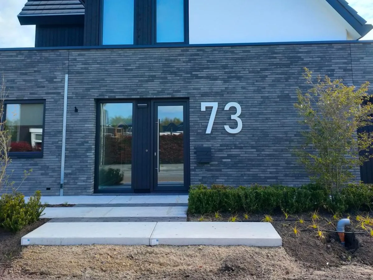 Edelstahl Hausnummer 73 an moderner Fassade in Bahnschrift, 80 cm hoch – stilvolle Außengestaltung