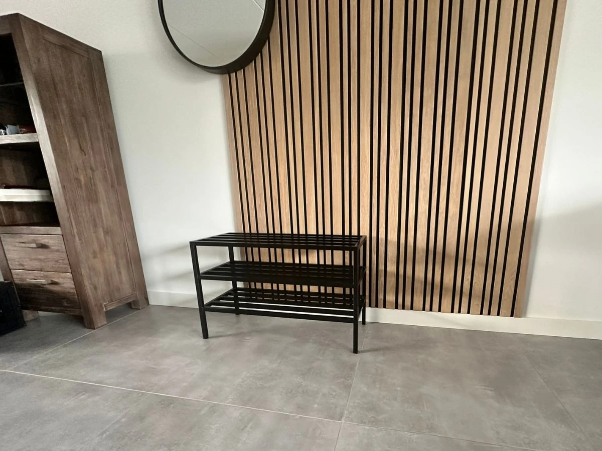 Edelstahl-Schuhregal in Schwarz in einem modernen Interieur mit Holzlamellenwand und Betonboden