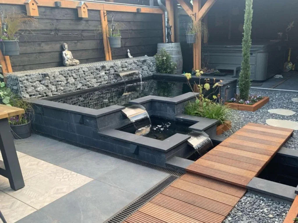 Moderne Teichanlage mit zwei Edelstahl Überlaufwasserfällen, Gabionenwand und Holzsteg im Garten.