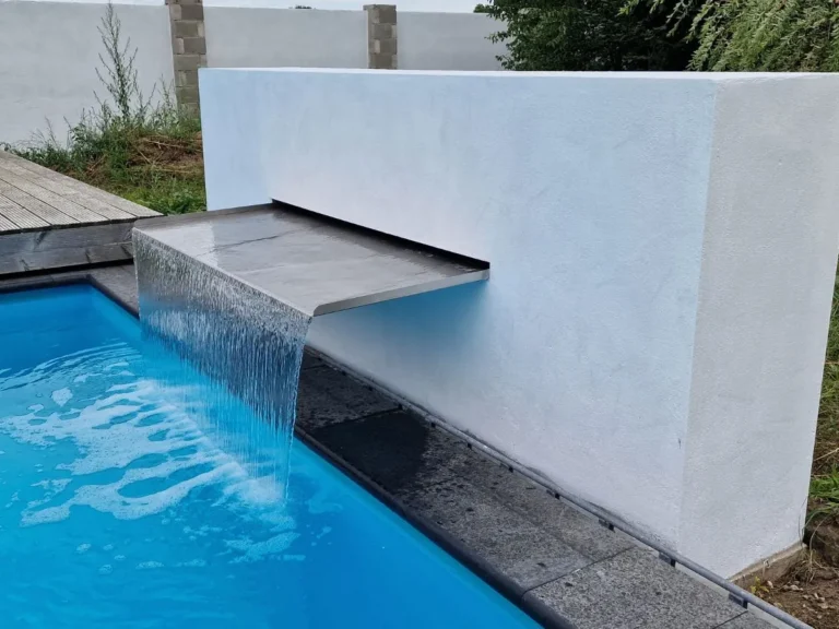 Breiter Überlauf-Wasserfall aus Edelstahl an weißer Wand neben einem modernen Pool
